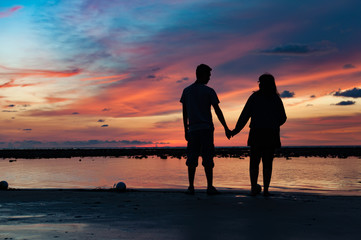 Silhouette of couple hold each other hand at the beach
