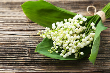 Lily of the Valley with leaves on brown wooden background