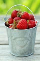 Strawberries berry in bucket on grey wooden background
