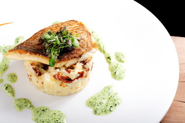 Tasty healthy fish fillet with potato puree with dried tomatoes and wild garlic sauce