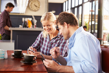 Obraz na płótnie Canvas Man and woman using smart phones at coffee shop