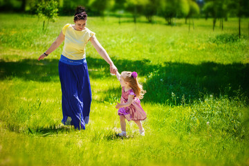 The little girl together with mother run and play on a grass in