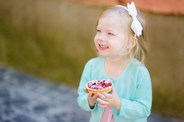 Adorable little girl eating fresh strawberry cake