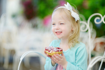 Adorable little girl eating fresh strawberry cake