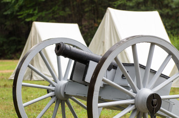 Vintage civil war era cannon and canvas army tents.