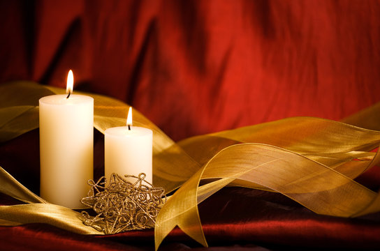 Christmas Candles, gold ribbon and holiday ornament with rich red background and some copy space. 