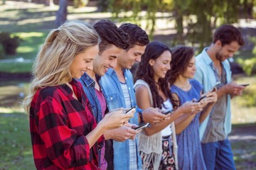 Happy friends in the park using their phones