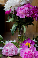 white and pink peonies bouquet from flowers market on a dark wood table in rustic style