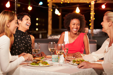 Group of female friends eating dinner at rooftop restaurant