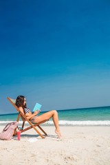 Pretty brunette reading a book on deck chair