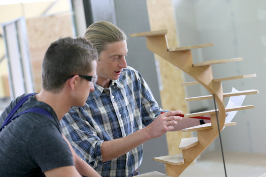 Apprentice with adult in carpentry school working on wood