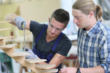Apprentice with adult in carpentry school working on wood
