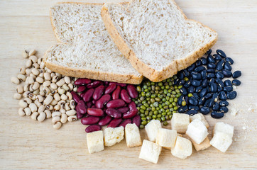 Wheat bread amd beans on wooden background.
