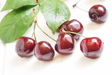 Ripe black cherry on a white wooden background, selective focus