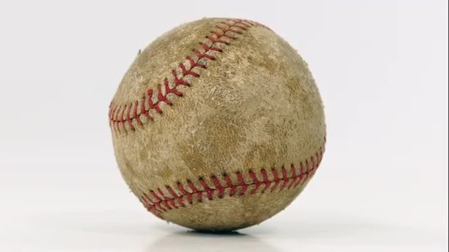 Grungy old baseball rotating on white.
