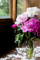 white and pink peonies bouquet from flowers market on a dark wood table in rustic style