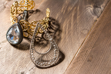 Jewelry on vintage background, beautiful shadow. Oval pendant, earring and golden bracelet on wooden background