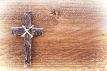 Hanging wooden cross on old rustic wood background