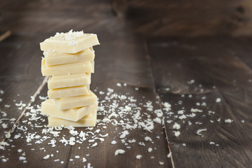 White chocolate shavings and chocolate pieces on color wooden background
