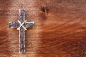 Wooden cross on old rustic wood background. The spotlight is on the holy cross