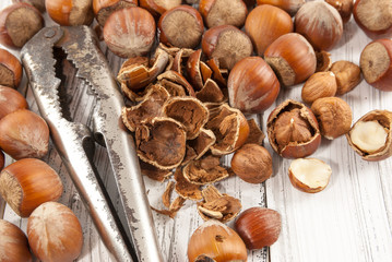 Close up of an old nutcracker and hazelnuts on white wooden background