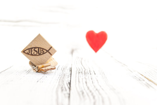 Christian fish symbol carved in wood and red heart on white vintage wooden background