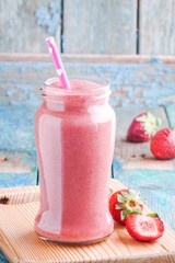 strawberry smoothie in a jar with a straw
