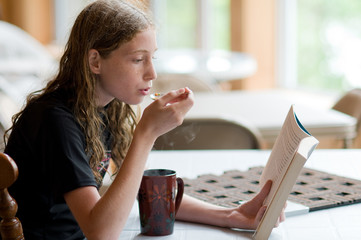 girl reading a book eating soup