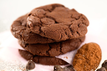 Stack of Double Chocolate Chip Cookies with a few of the ingredients used: Cocoa and chocolate chips. 
