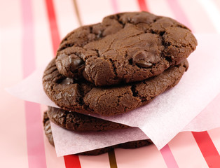 Stack of Double Chocolate Chip Cookies on pink and red striped background. 