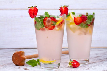 Lemonade with fresh strawberries mint and lemon on wooden background