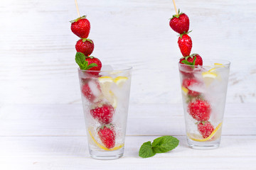 Lemonade with fresh strawberries mint and lemon on wooden background
