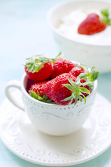 Fresh strawberries in a rustic cup on wooden table