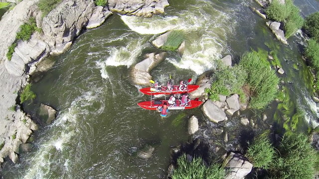 Tourists by  boat sat down on  stone. Aerial  view of rafting team

