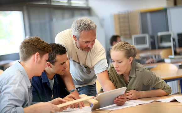 Teacher With Group Of Students Working On Digital Tablet