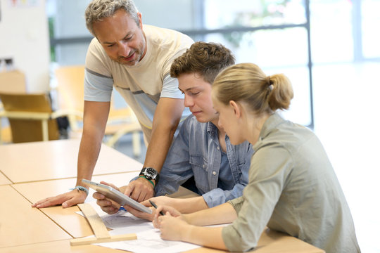 Teacher With Group Of Students Working On Digital Tablet