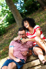 Charming young couple sitting on stairs in the park and blowing bubbles.