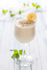 Healthy banana smoothies with oatmeal in a glass on a blue background