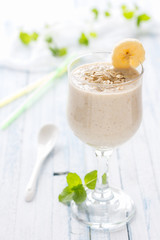 Healthy banana smoothies with oatmeal in a glass on a blue background