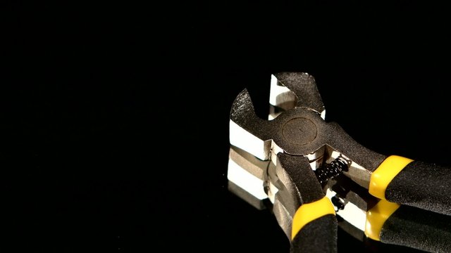 Part of wire cutters with yellow, gray handle on black