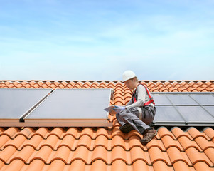 Man on roof top checking on solar panel installation