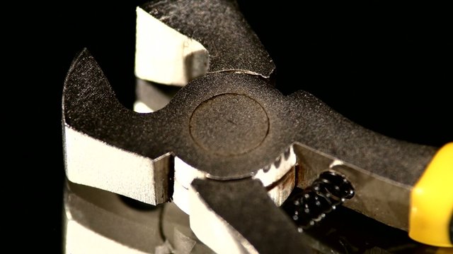 Part of wire cutters with yellow, gray handle on black