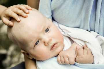 Frightened little baby boy resting in mothers arms