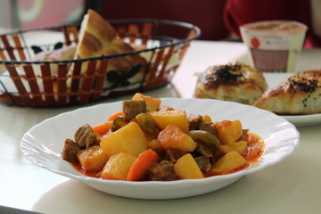 Nice lunch. Roast with vegetables, pies with meat and cumin and bread on the table.