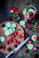 strawberry mint cucumber infused water decorated in rustic style on dark wood table background