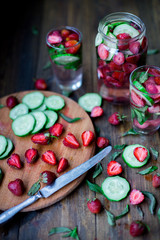 strawberry mint cucumber infused water decorated in rustic style on dark wood table background