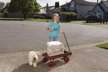 Young girl delivering newspapers with her dog.