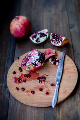 organic pomegranate open cut in half and full one on a wooden dark table background decorated in rustic style