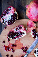 organic pomegranate open cut in half and full one on a wooden dark table background decorated in rustic style