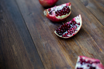 organic pomegranate open cut in half and full one on a wooden dark table background decorated in rustic style